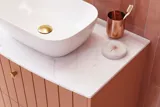 Large vintage retro bathroom inspiration with a terracotta-colored grooved vanity, elegant thin countertop with a beautiful vessel sink, stylish oval mirror with brass edge. Pink tiles and grey herringbone tiles give a romantic and feminine look